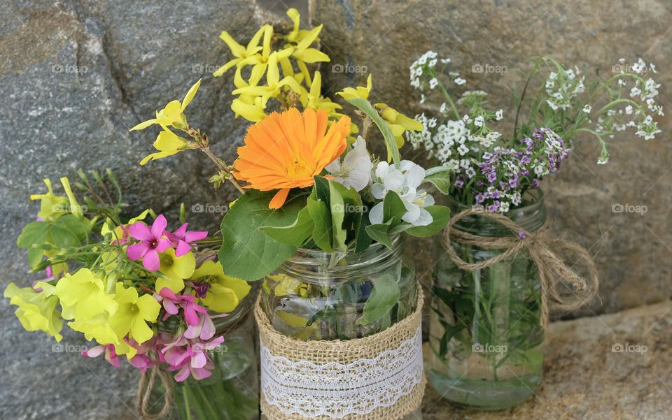 Common garden flowers and blossoms in rustic glass jars 