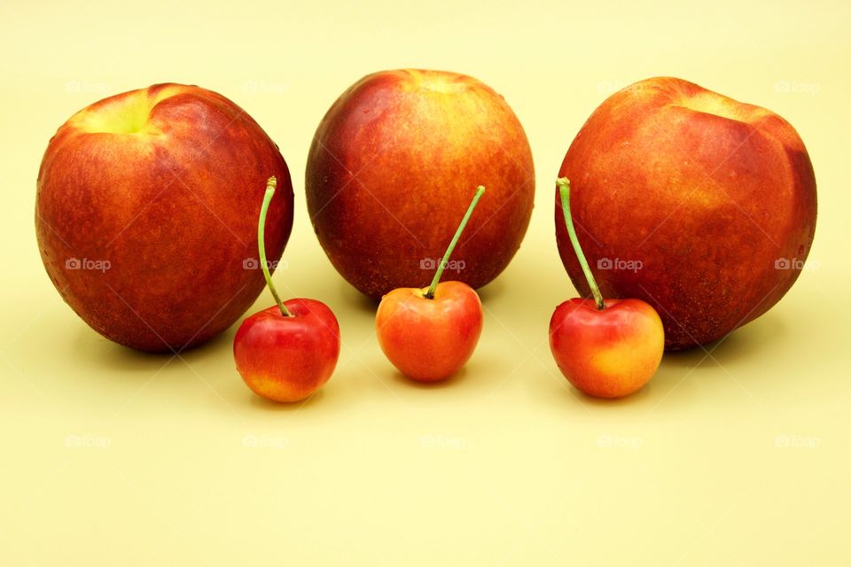 Fruits! - Nectarines And Rainer cherries against a yellow background 