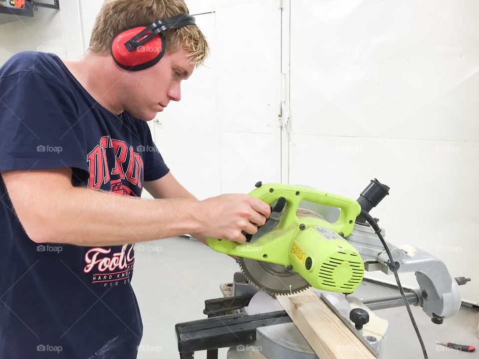Man working with a cross-cut saw in a construction site.