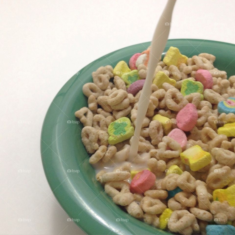 Pouring milk over Lucky Charms cereal in green bowl