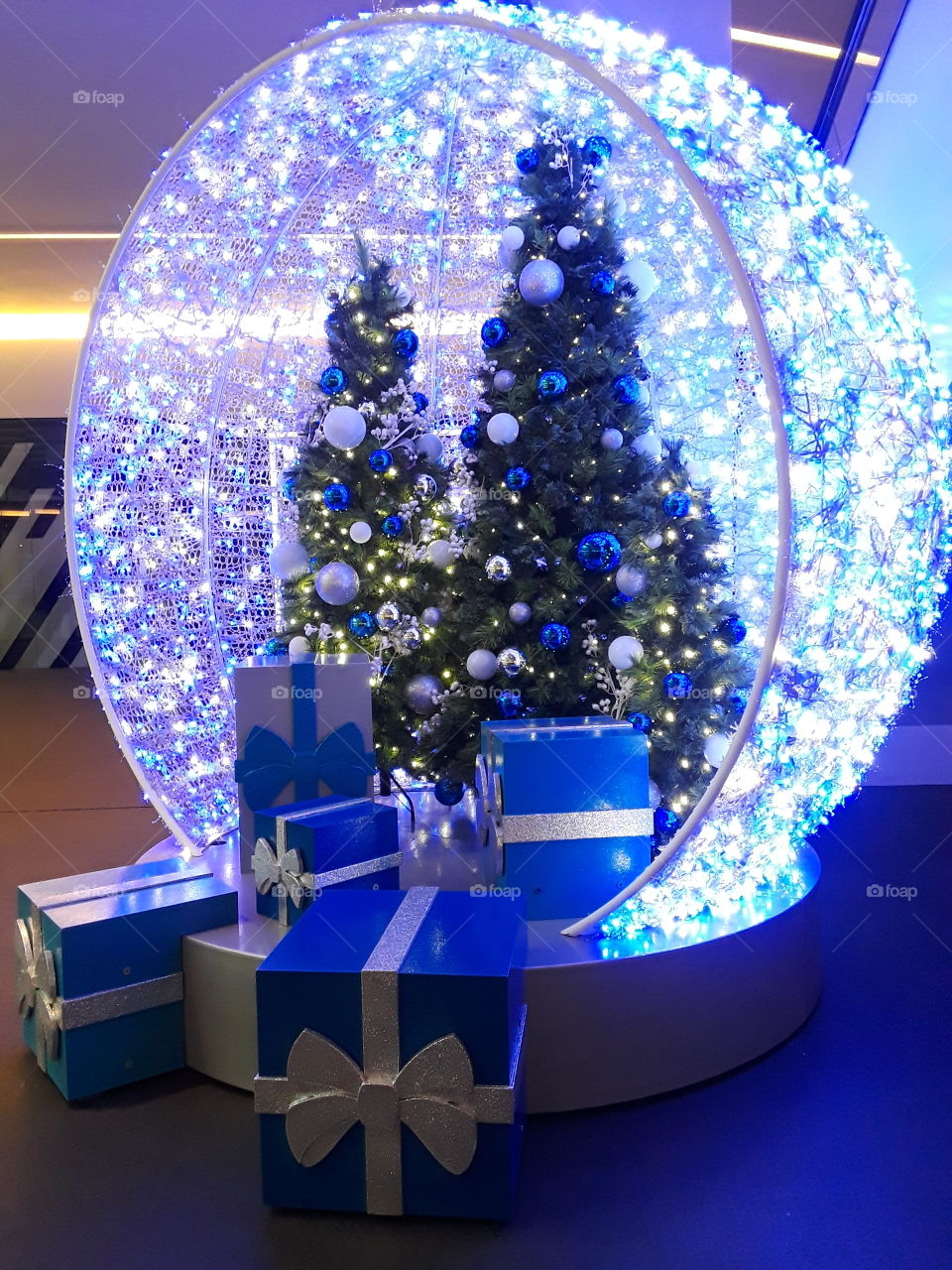 esfera navideña con luces de color azul,  árbol navideño con esferas y regalos navideños, festividad navidad