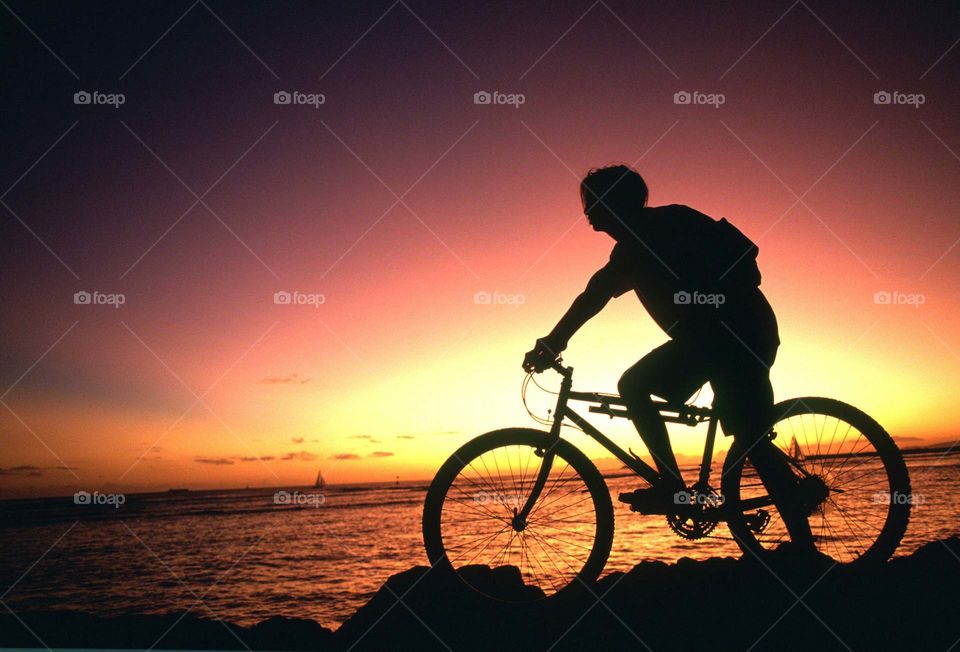 Man riding his bike through the sunset