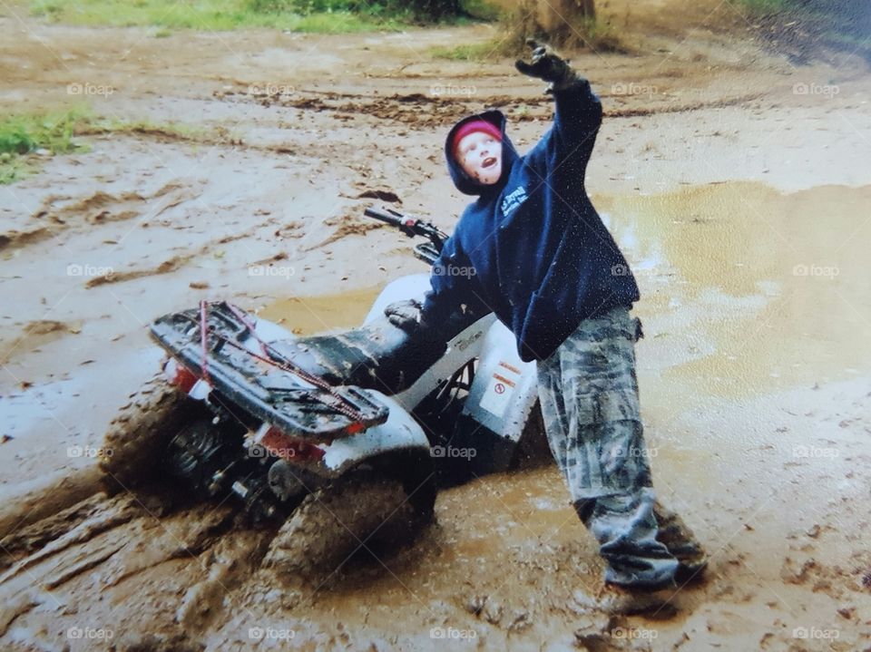 Teenager boy with quad bike on mud