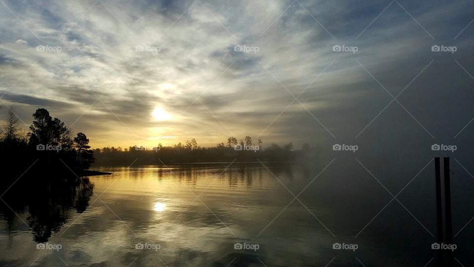 sunrise looking like a smeared painting as fog obscures the lake.