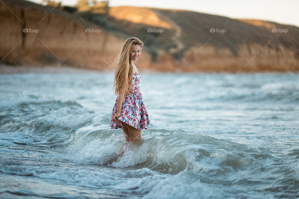 Portrait of beautiful young woman near the sea at sunset