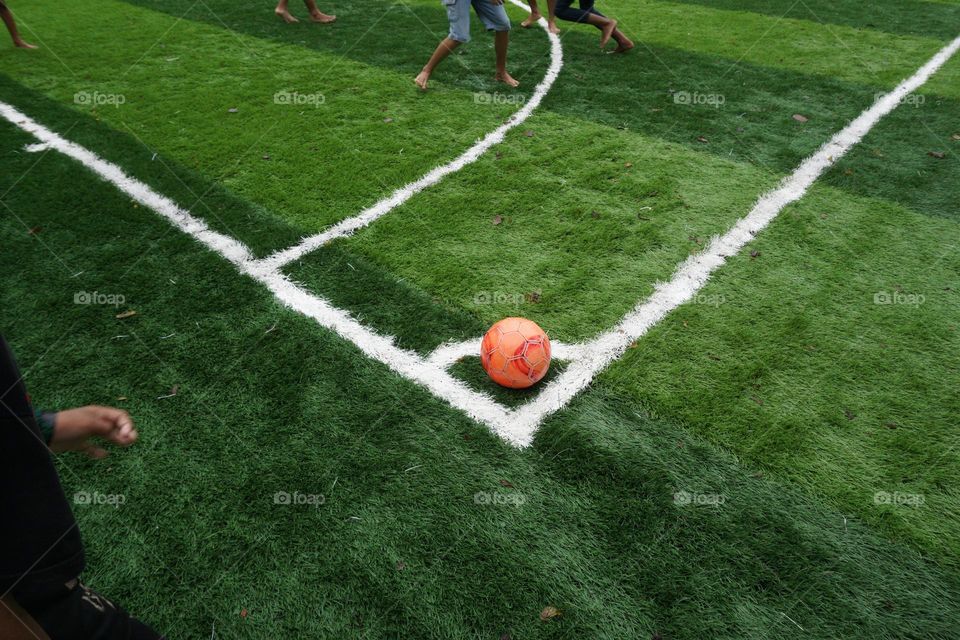 some children who are playing football with the ball in the corner of the field