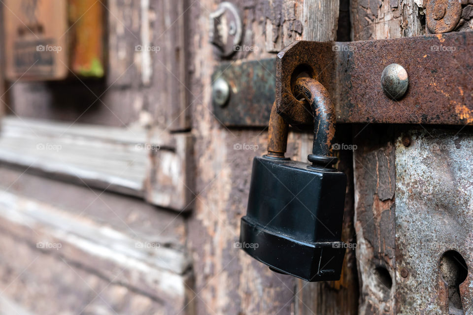 Padlock on old door with damaged color.