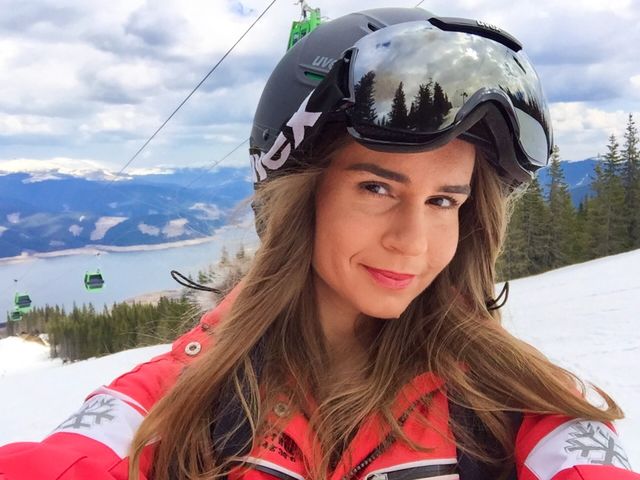 Portrait of woman skier wearing Uvex ski glasses and Uvex helmet with ski lifts in the background 