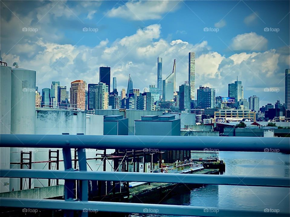 A view of „Newtown Creek“, an ocean inlet of the „East River“ from the „Brooklyn Queens Expressway“ on route to „Fort Greene“. The „Manhattan skyline“ is visible in the distance. 2022. Hypnotic Productions