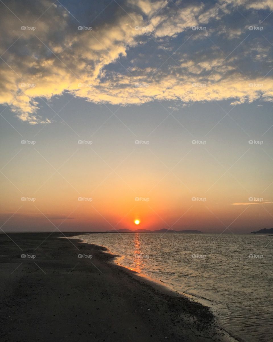Scenic view of beach against sunset sky