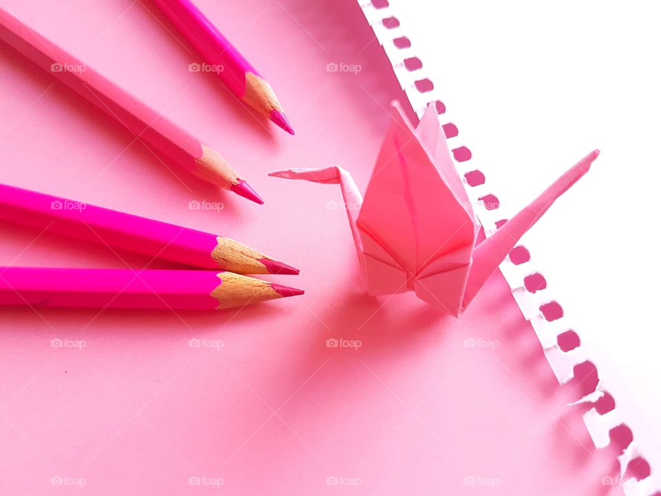 Pink paper crane and colored pencil