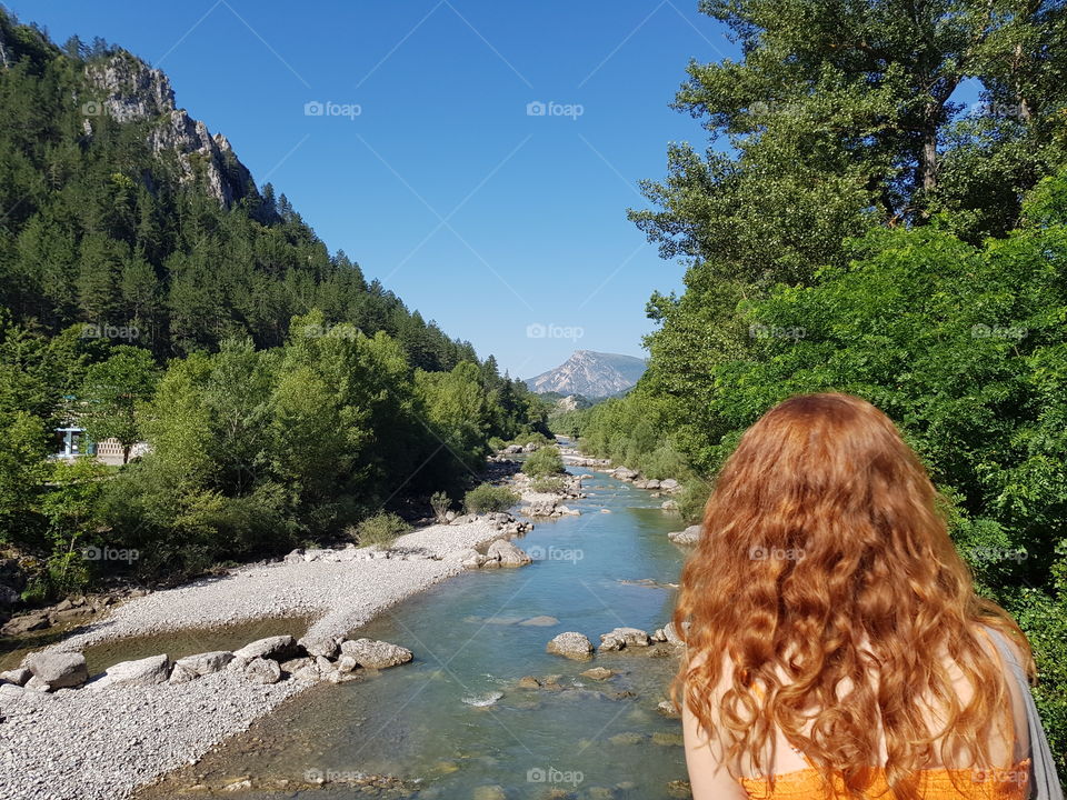 Young redhead woman looking out at Verdon river in castellane,  France.