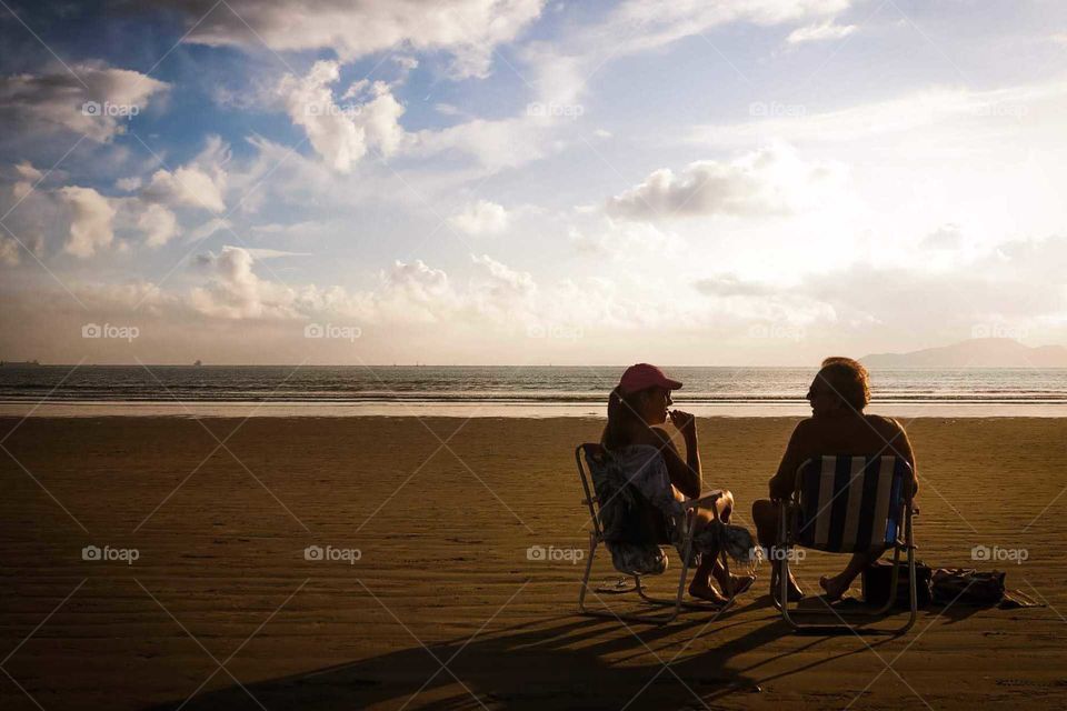 Couple sitting at the Sunset, in Santos, Brasil. Beautiful Golden hour shot.