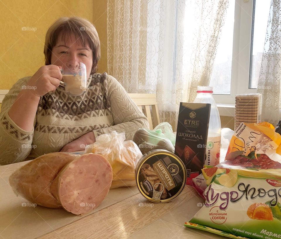 Woman with the different meals is drinking a tea 