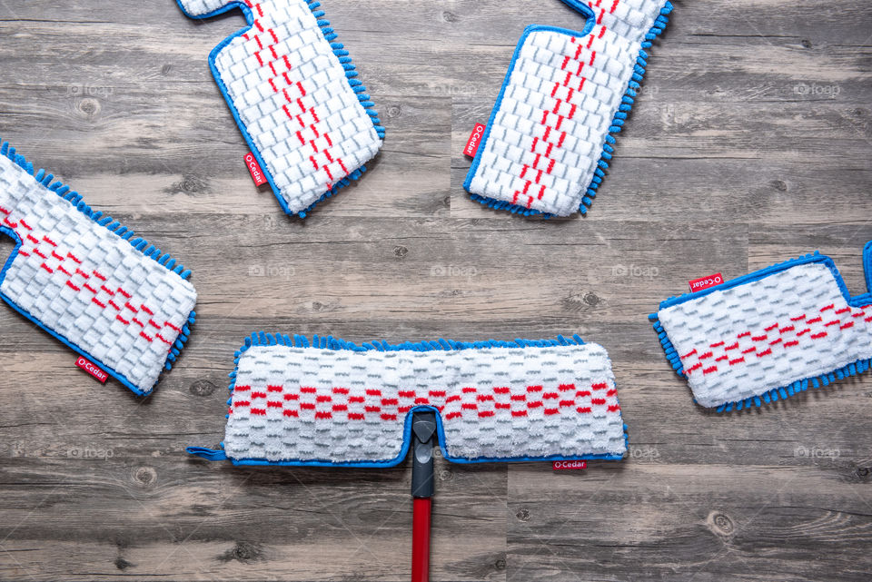 Flat lay of an O-Cedar mop and microfiber mop head refills on a hardwood floor