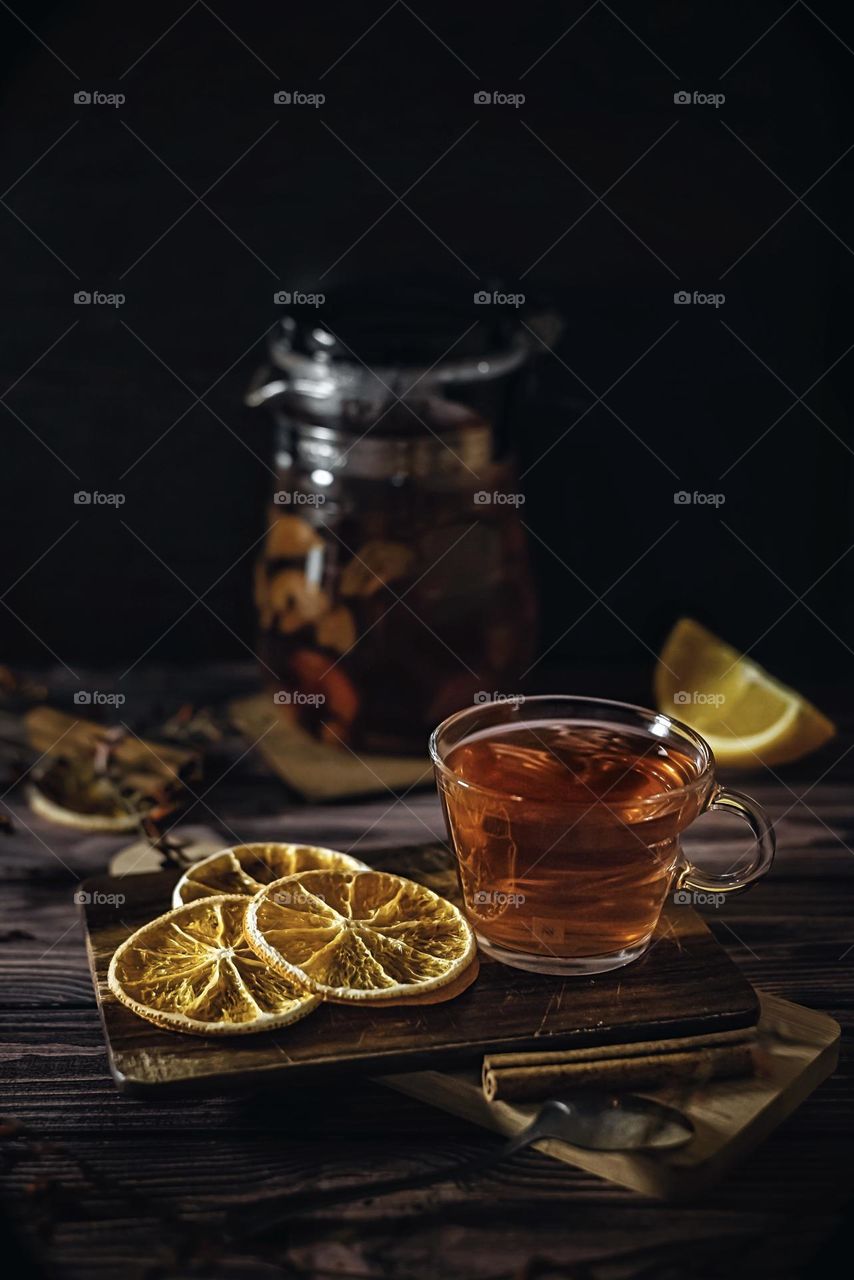 Food still life style dark key, citrus tea in a glass cup and oranges on a black background