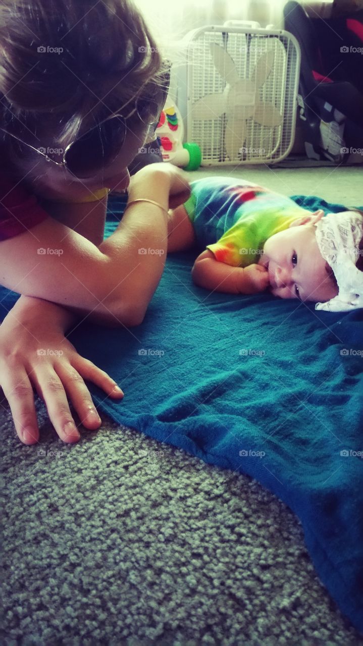 Girl playing with baby lying on blanket