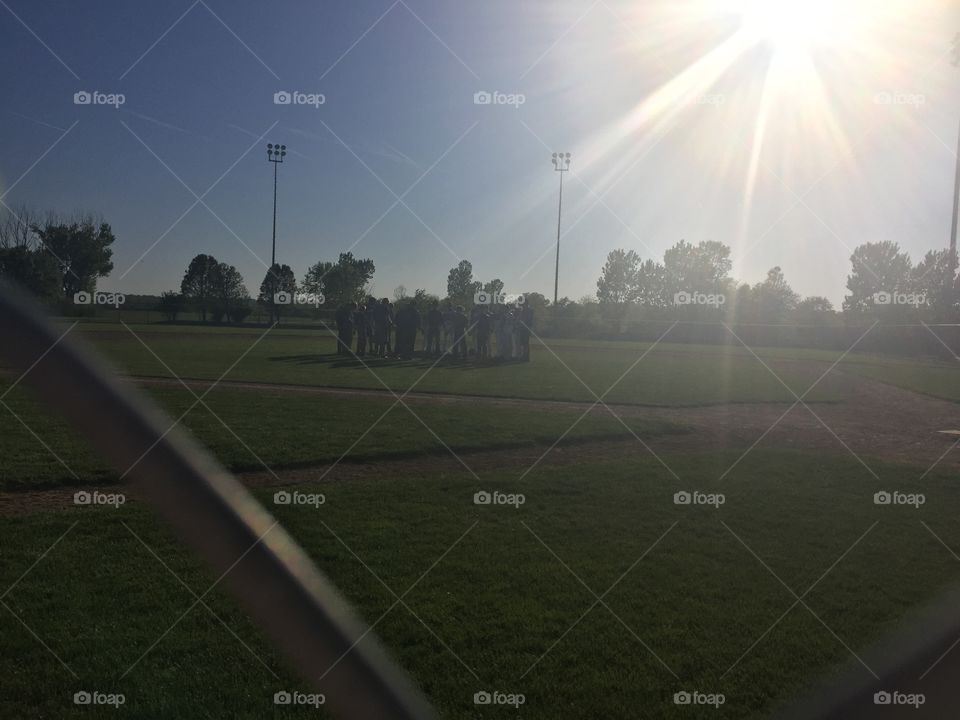 Sunrise over the baseball team praying on the pitching mound.