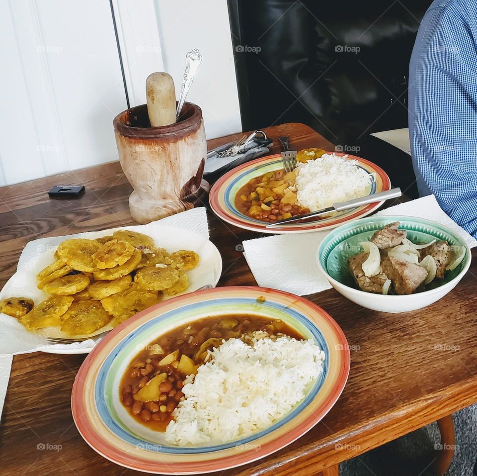 arroz Jasmin blanco, habichuelas rosadas guisadas tostones y biftec encebollado. (white Jasmin rice, stewed pink beans, fried green plaintains, beefsteak with onions)