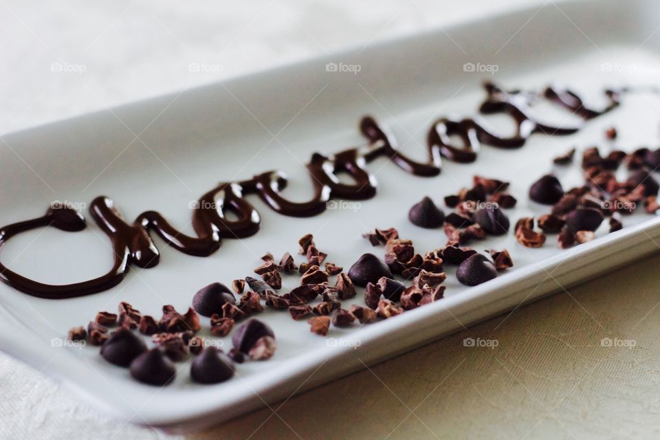 More Chocolate - rectangular white dish with scattered cacao nibs and chocolate chips, and the word "Chocolate" written in chocolate drizzle