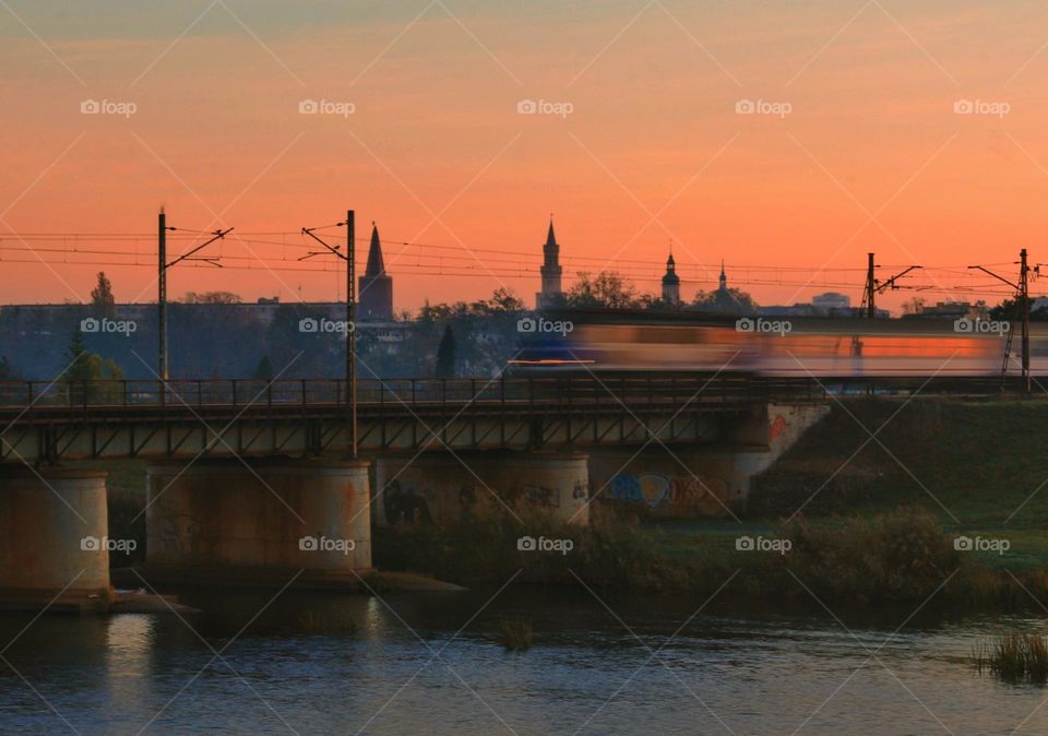 the train against the background of the sunrise and the towers of churches and the town hall