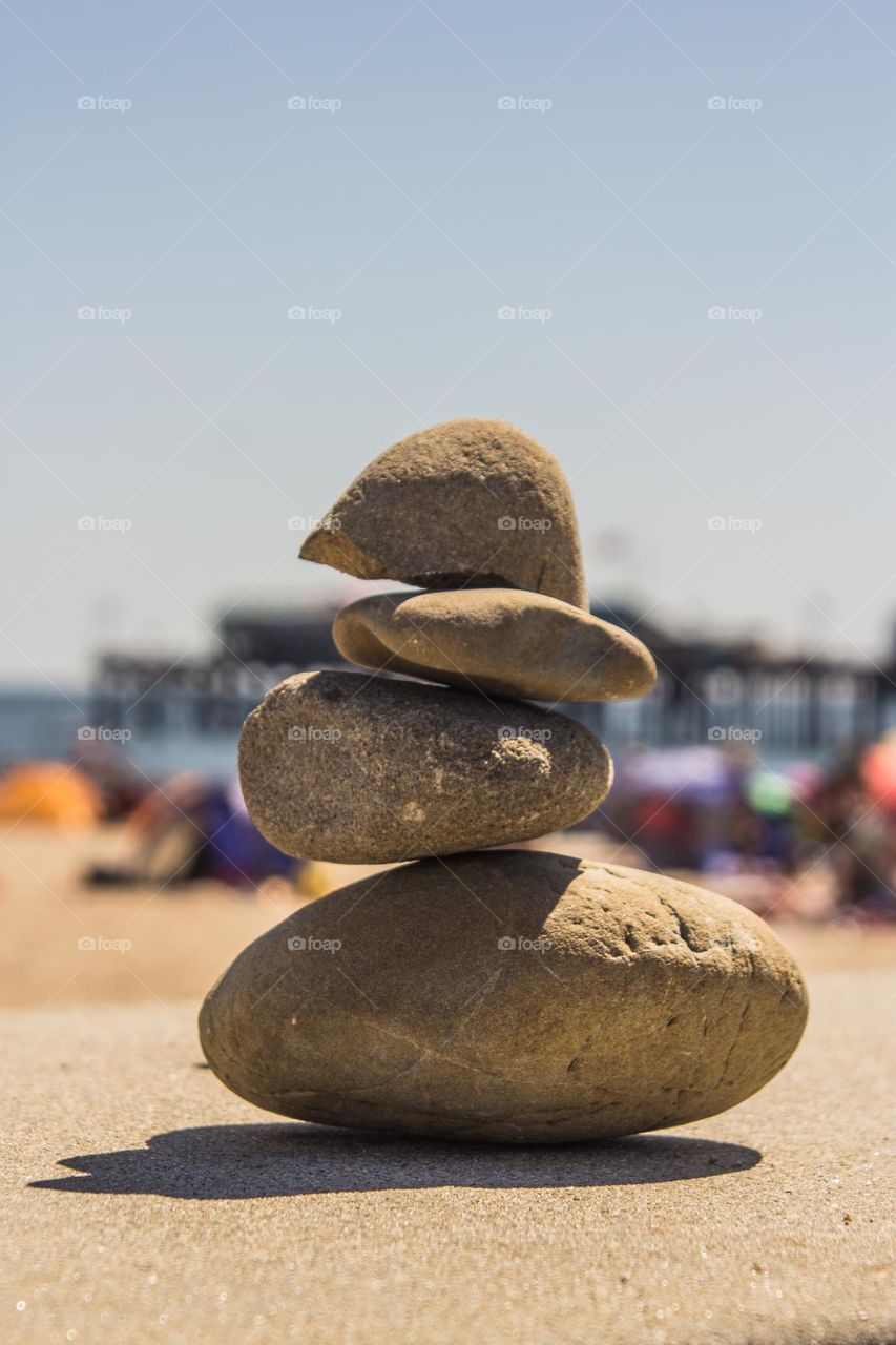 Small stack of rocks that almost looks human on a warm summer’s day with the beach in the background 