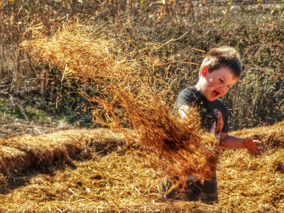 Cute boy throwing hay