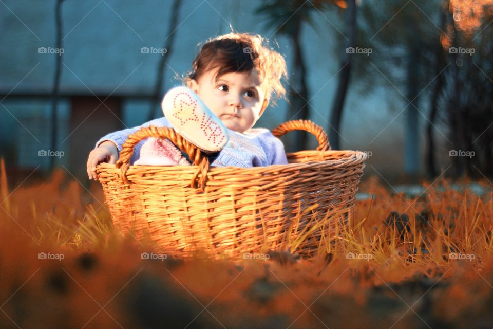 Little girl sitting in wicker basket