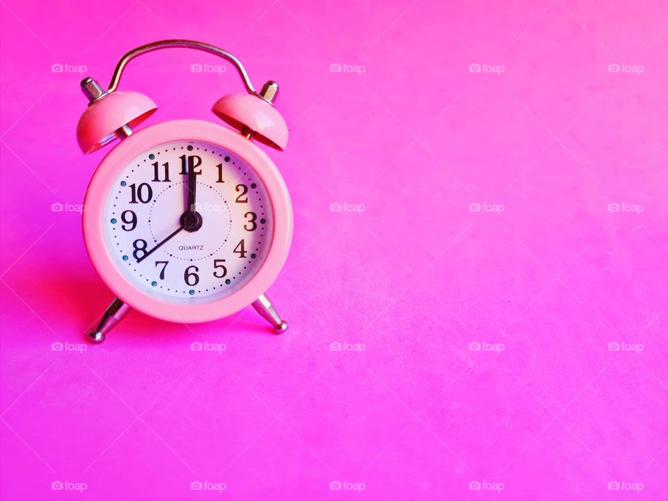 minimal photo of pink alarm clock on pink background (time concept)