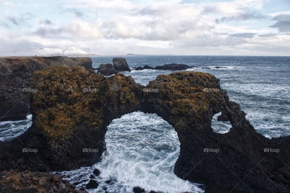 Rough nature in Iceland with natural big rock portal and ocean water flowing through.