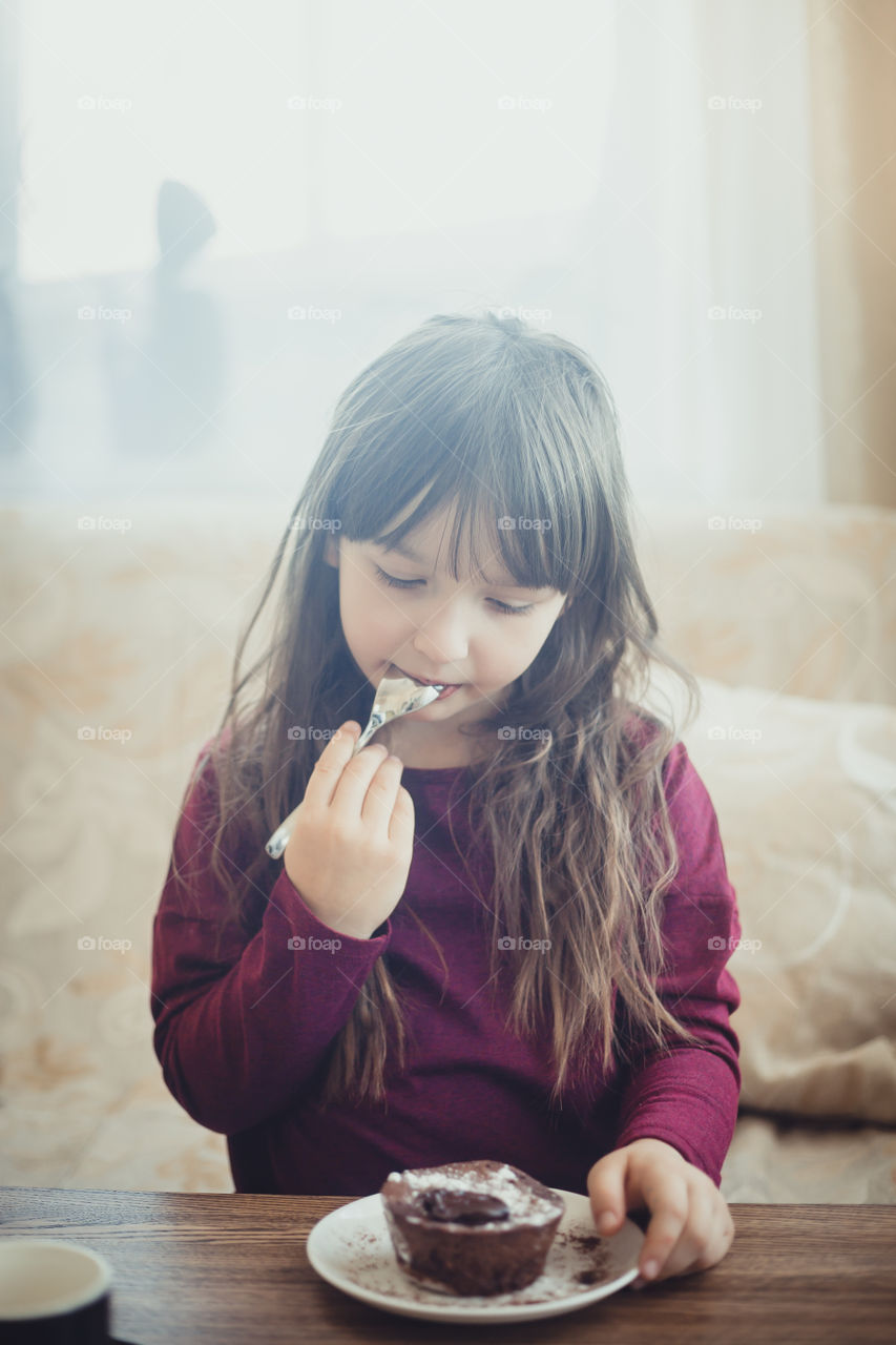 Little girl eating the chocolate muffin