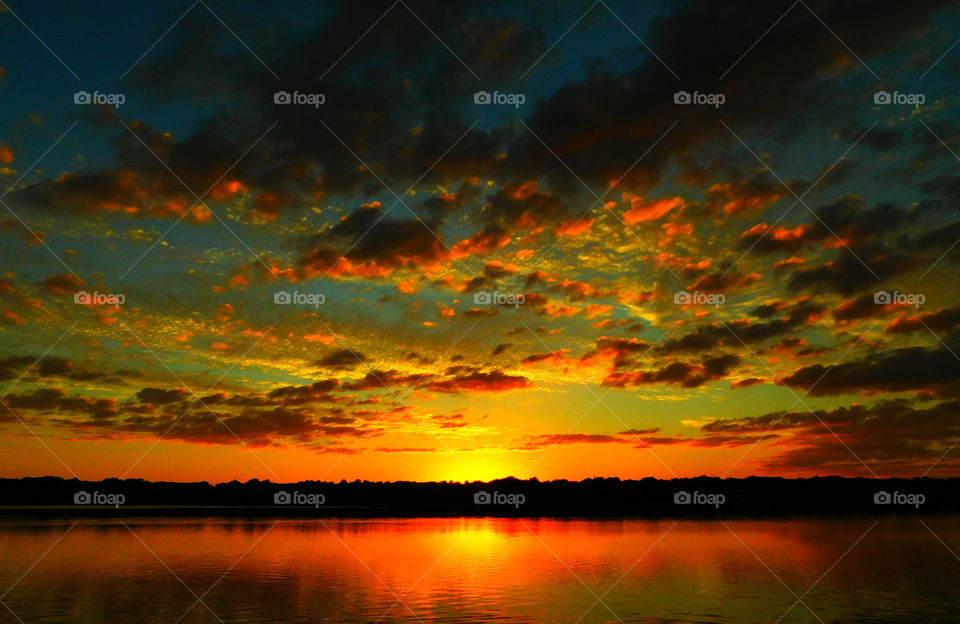 Magnificent cloud burst sunset. A magnificent array of colorful flowing clouds reflects from a shimmering sunset over the bay!