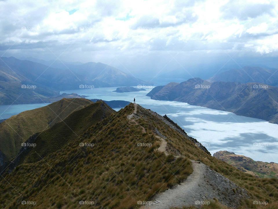 female silhouette on mountain next to a lake