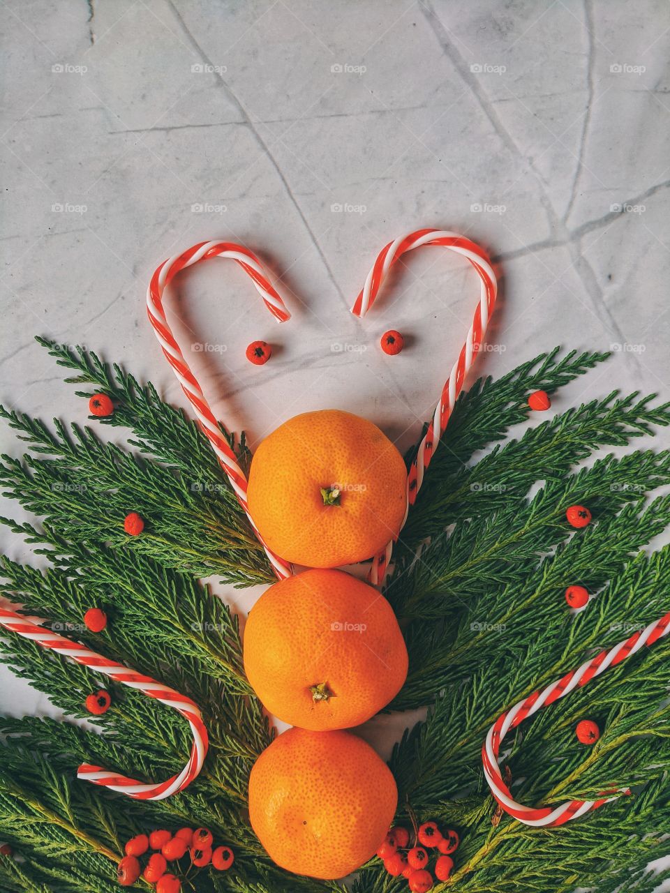 Christmas and New Year background with spruce branch, candies, decorations and tangerines Flat lay. Top view.
