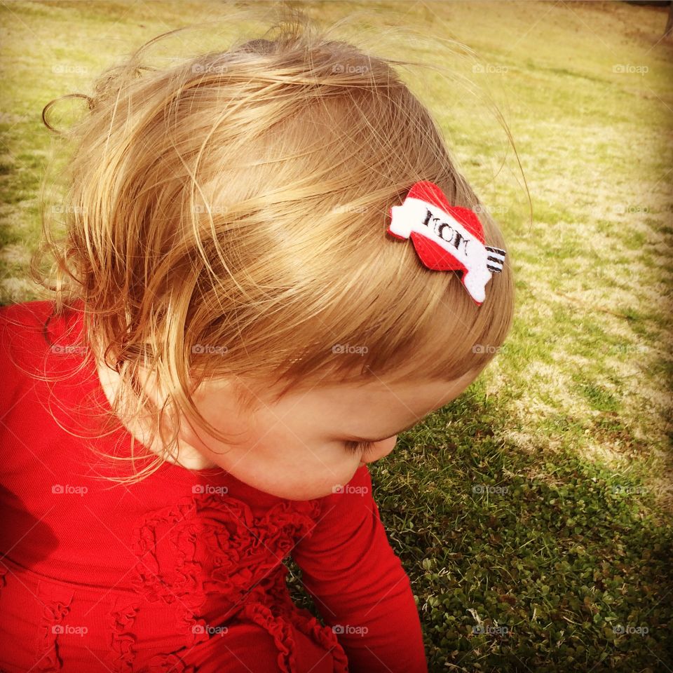 Baby girl with red dress showing off heart barrette with Mom tattoo design 