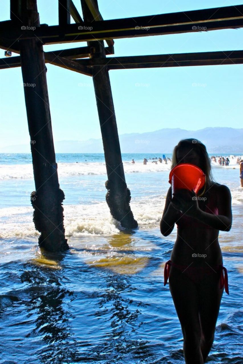 Silhouette of girl with red bucket at the beach 