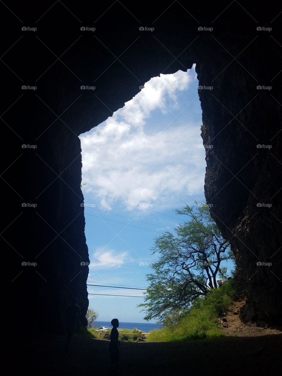 Boy poses at entrance to Makua Cave
