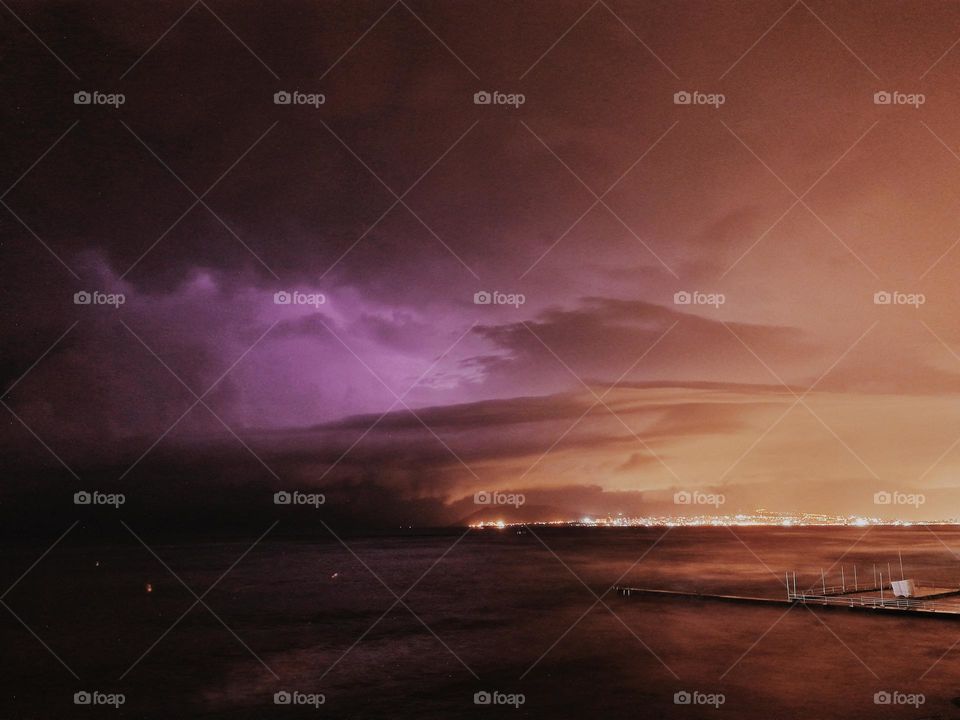 Storm by the sea, lightning over the night city