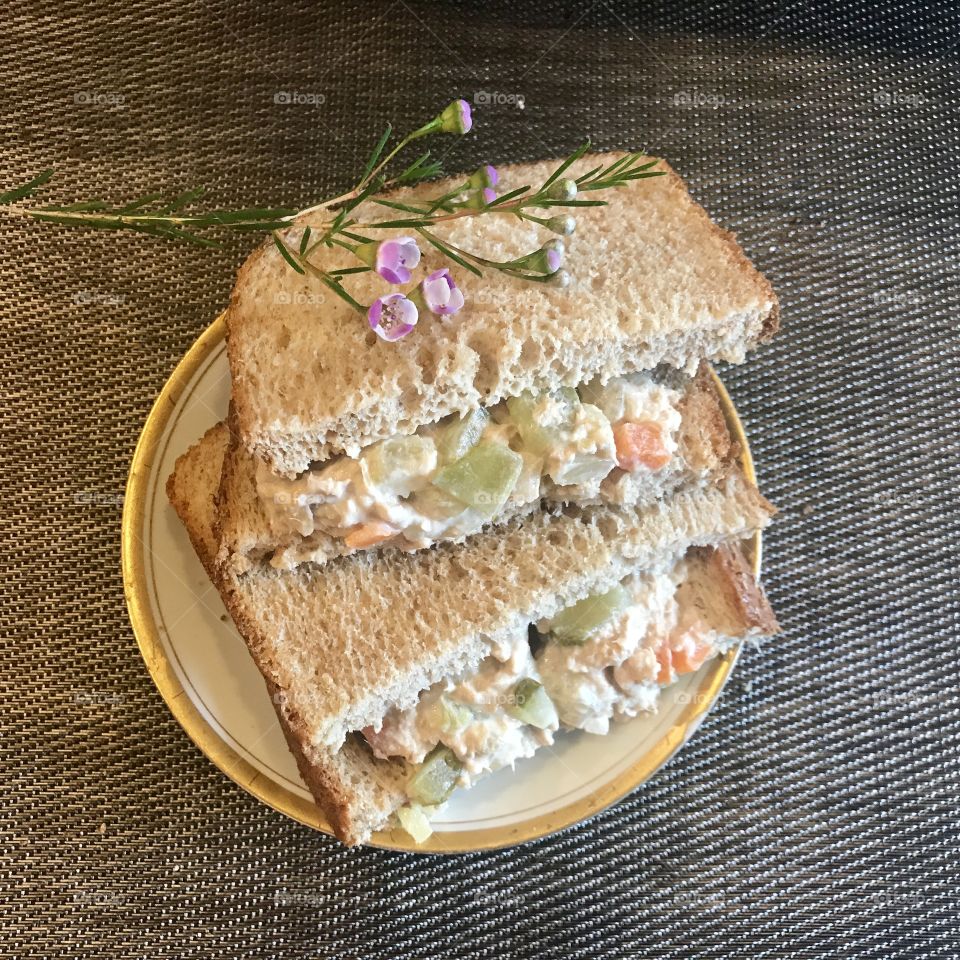 A healthy tunafish salad sandwich on white bread with celery and red bell peppers for lunch, with a purple flower . USA, America