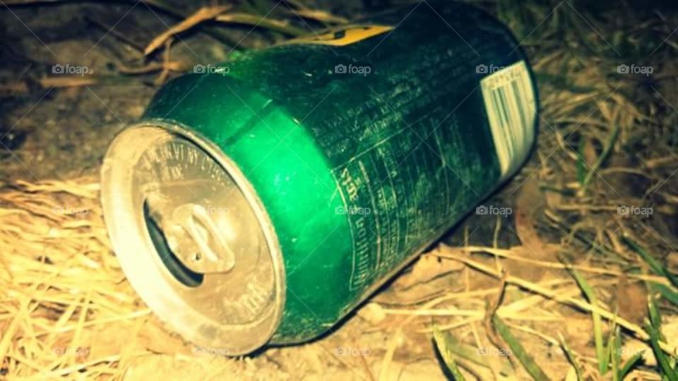 Alone and forgotten, the can lays in wait for someone to notice it. Green and shiny