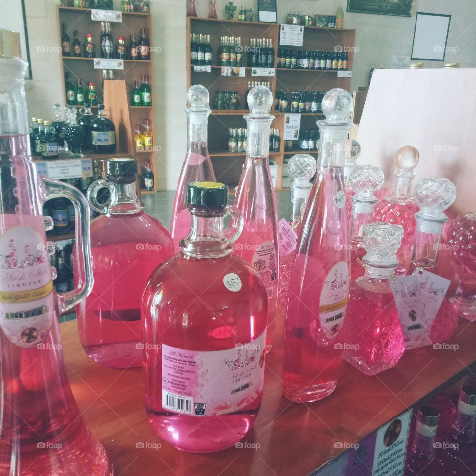 pink glass bottles of alcohol, all different shapes and sizes.