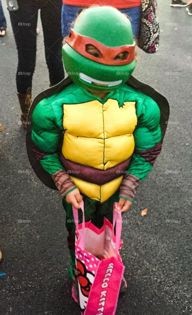 Child dressed in teenage mutant ninja turtle Halloween costume trick-or-treating