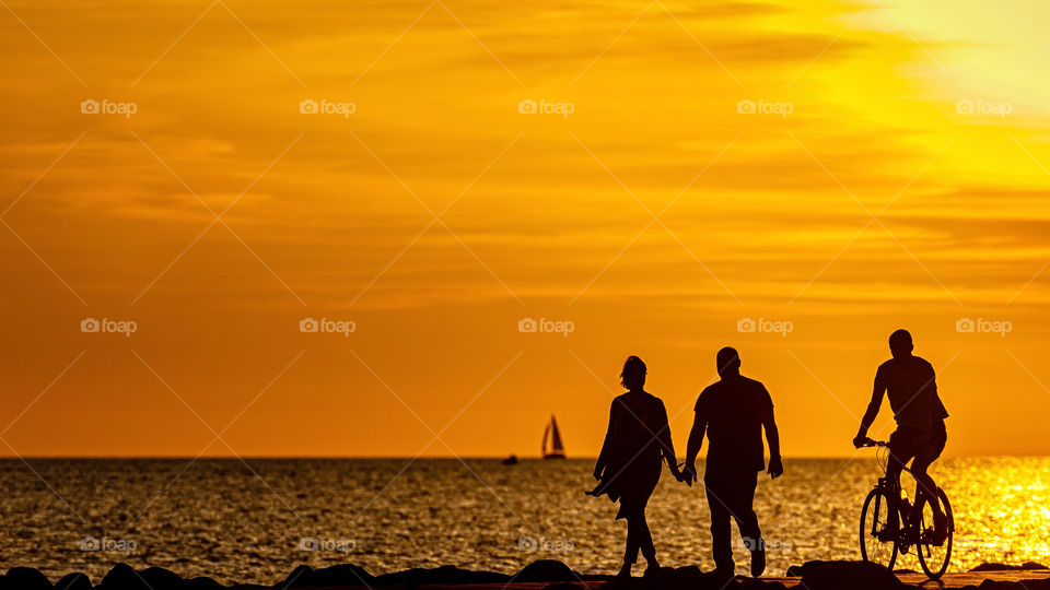 silhouette of couples walking on the pier during the golden hour of sunset