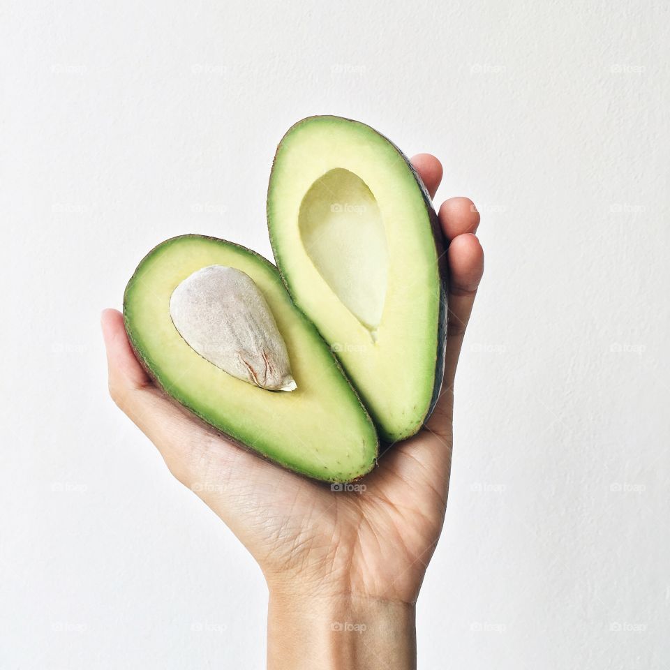 Person holding halves of avocado