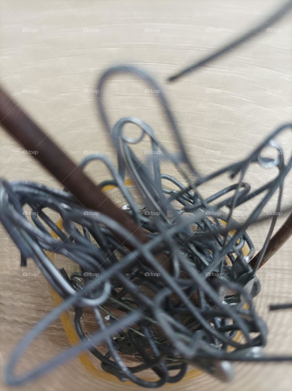 pregos e clipes em um copo em cima de uma mesa