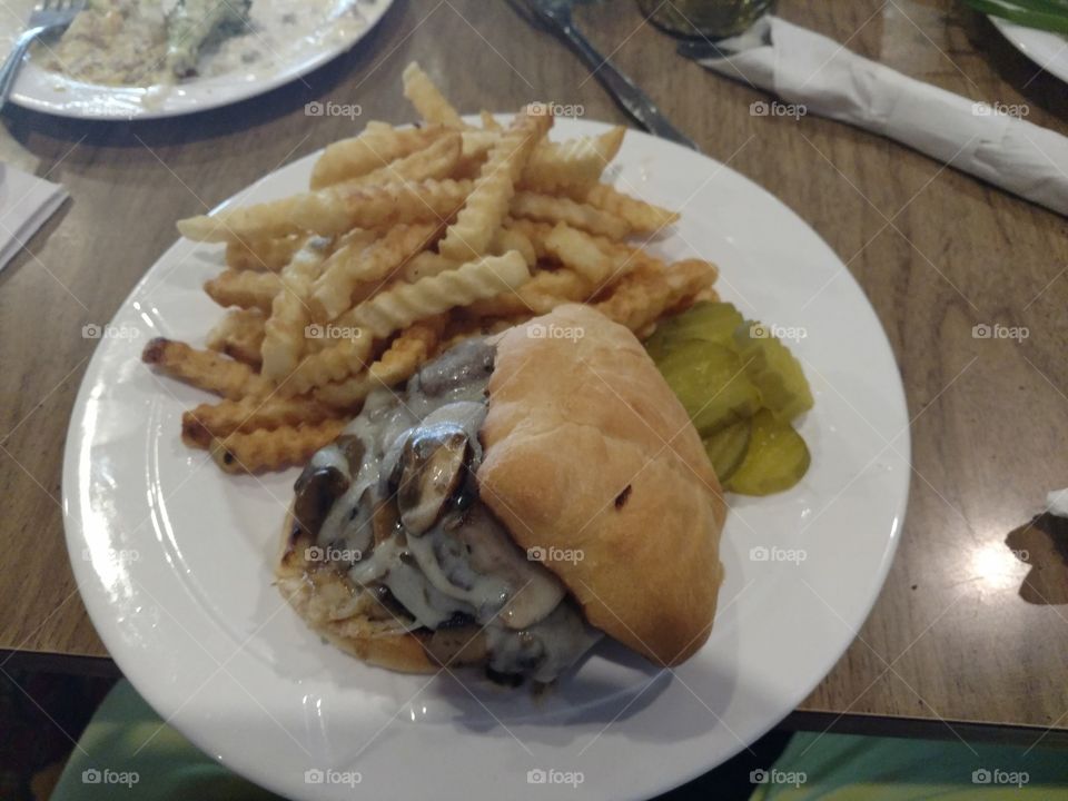 mushroom and Swiss burger with french fries and pickles for lunch