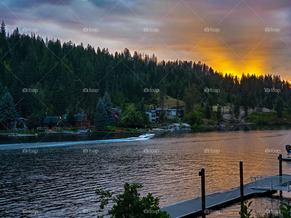 A magnificent sunset illuminates the overcast with a warm glow and is reflected on the Spokane River in Couer D'Alene Idaho