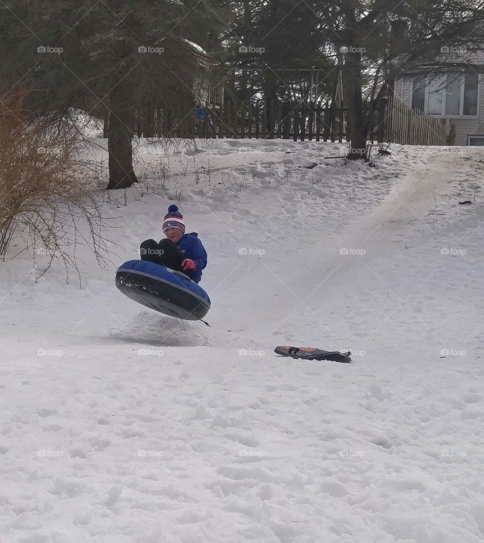 Little boy with skates lies on snow tube at winter day