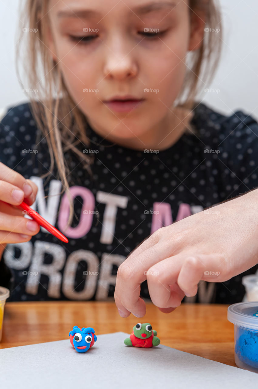 Girl working with plasticine on her miniature animal creatures.