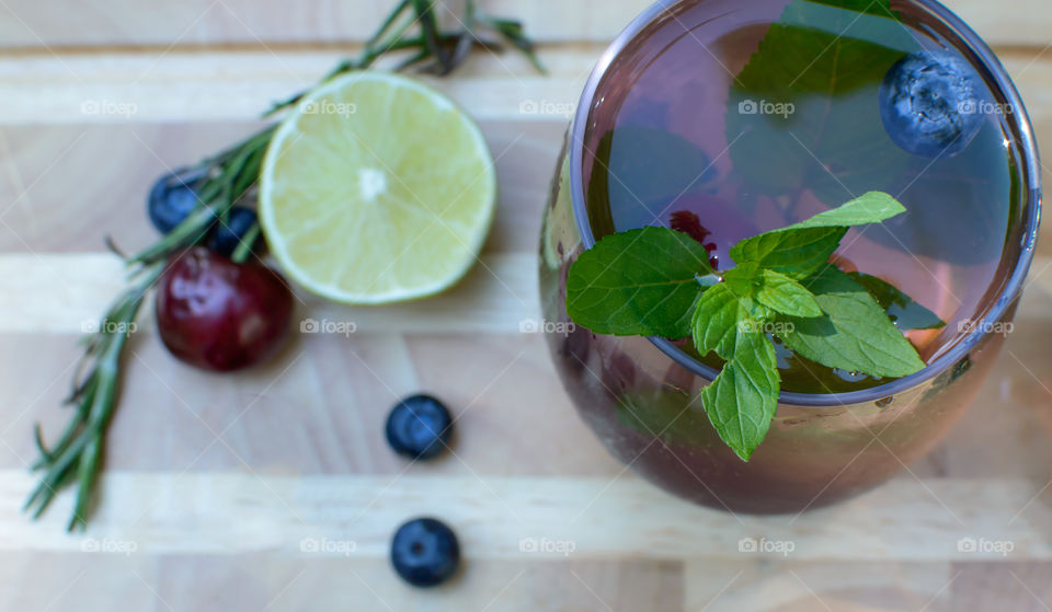 High angle view of fresh homemade blueberry, Rosemary  mint, citrus, cherry flavored water on wood table with healthy drink ingredients - summer drink photography 